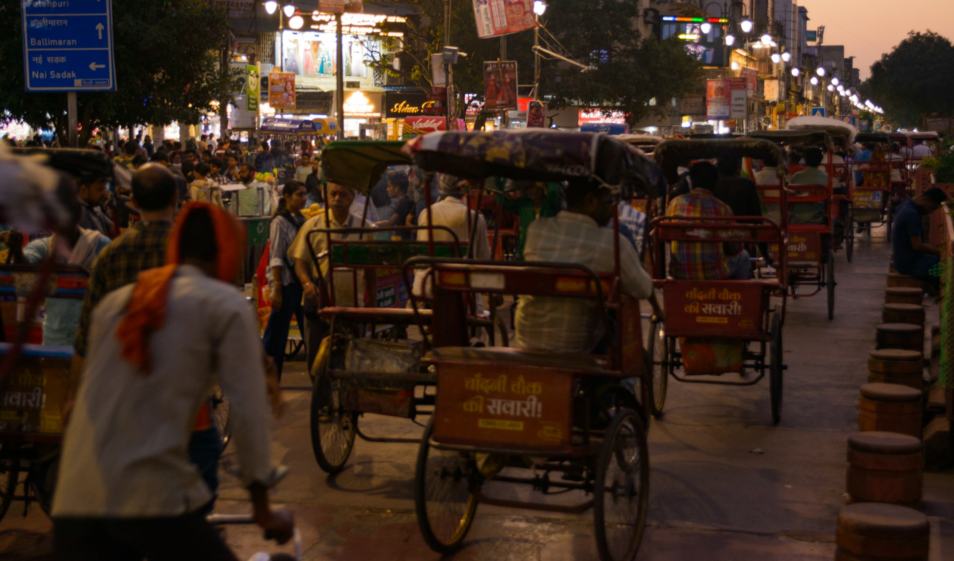 Rickshaws and people on a busy street at dusk